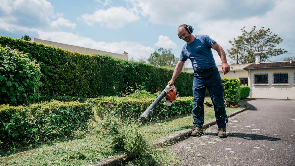 Un agent qui entretien l'herbe aux abords d'une route