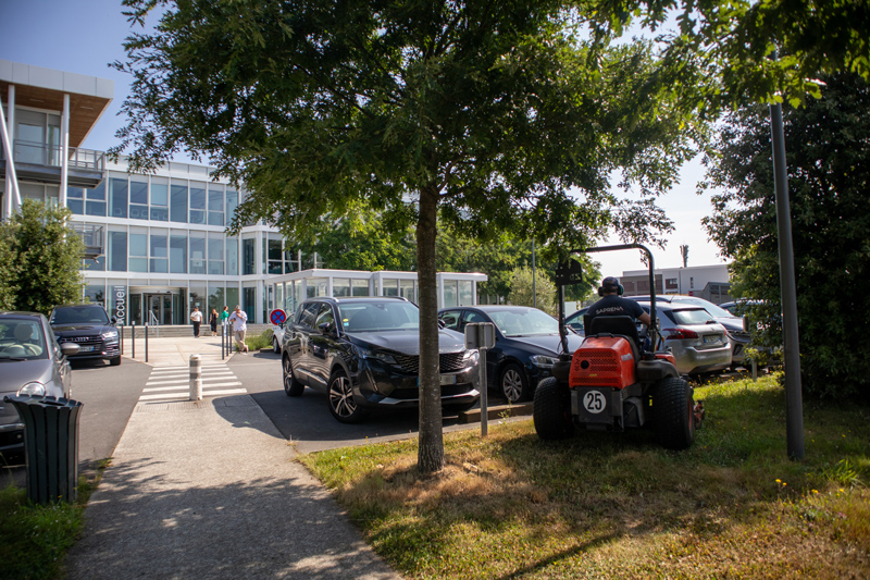 Un agent qui entretien les espaces verts devant le siège d'une entreprise