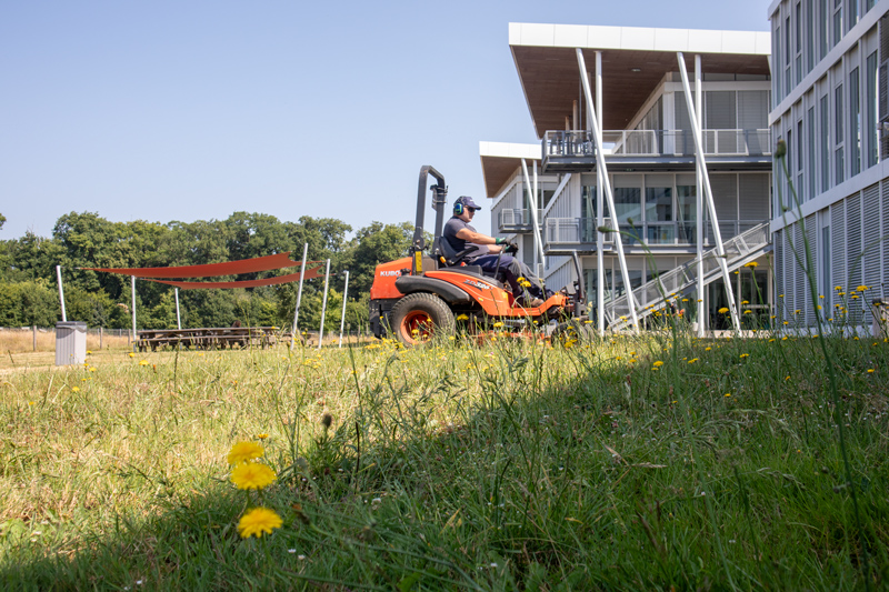 Un agent qui fauche l'herbe sur le site d'un siège social d'entreprise