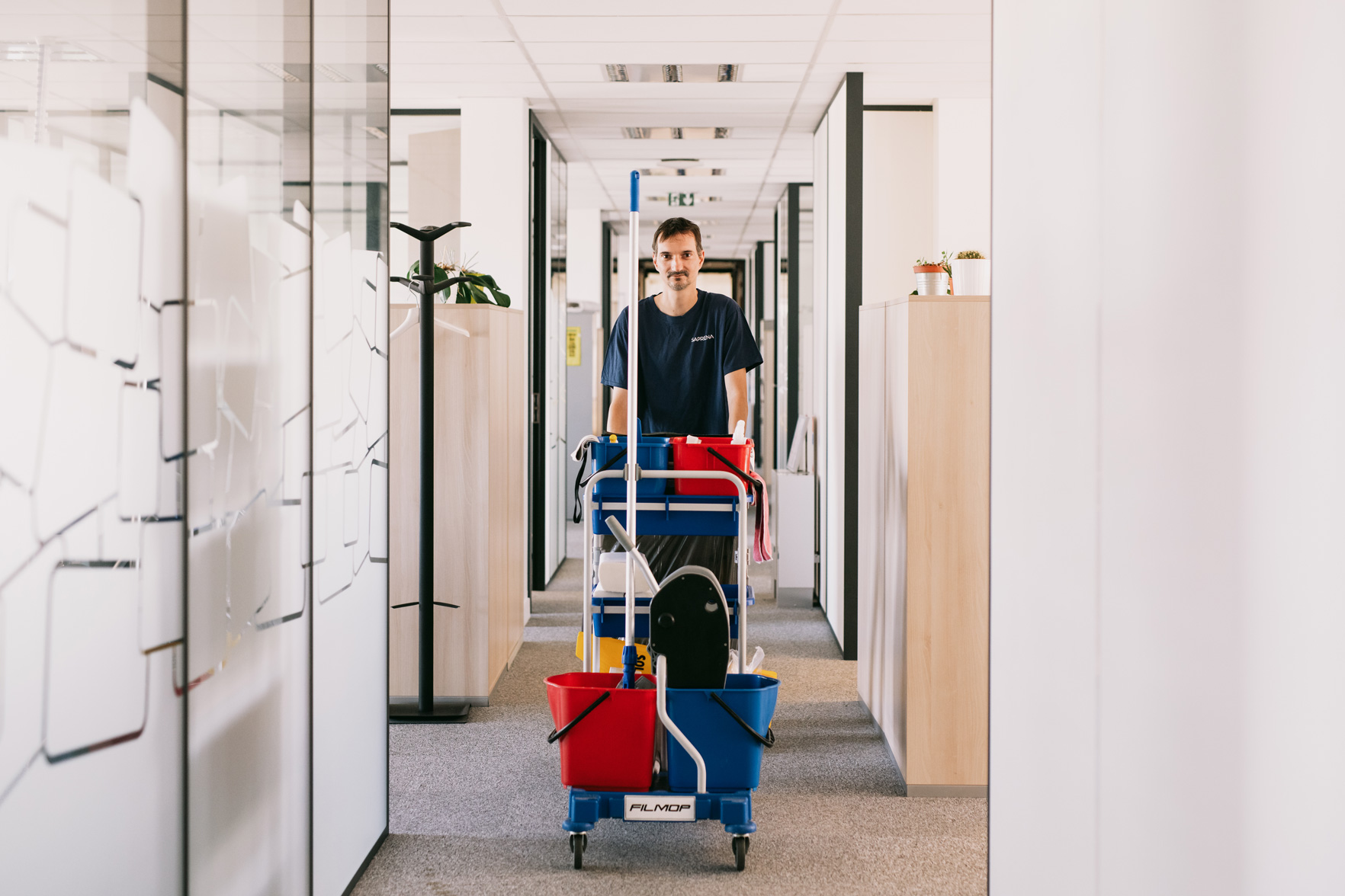 Un agent de propreté qui pousse son chariot de matériel d'entretien